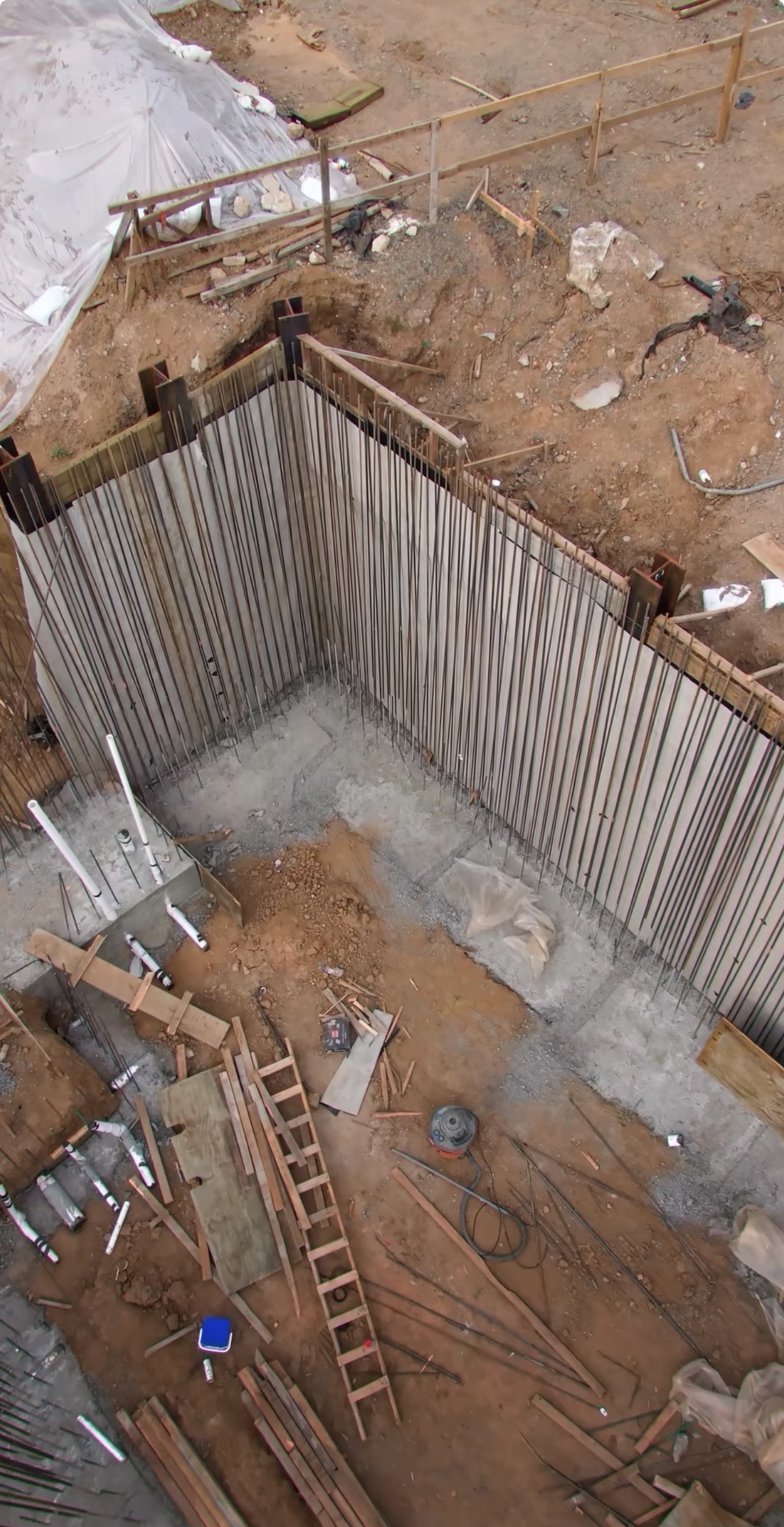 Overhead view of vertical steel rebar grid installed inside a deep elevator pit excavation