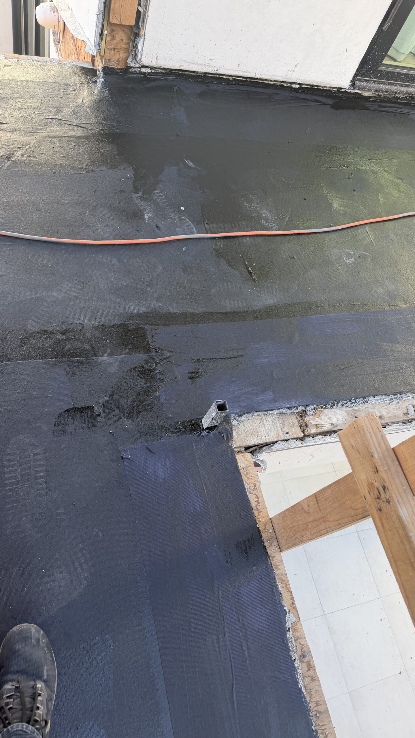 Black liquid-applied elastomeric waterproofing membrane coating on concrete ledge