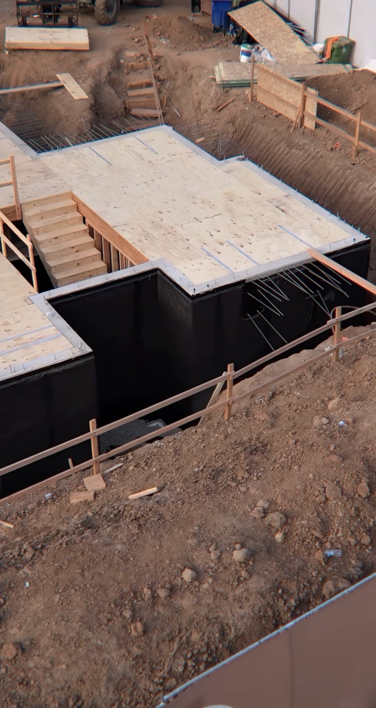 Black waterproofing membrane applied on below-grade elevator pit foundation walls in excavation trench
