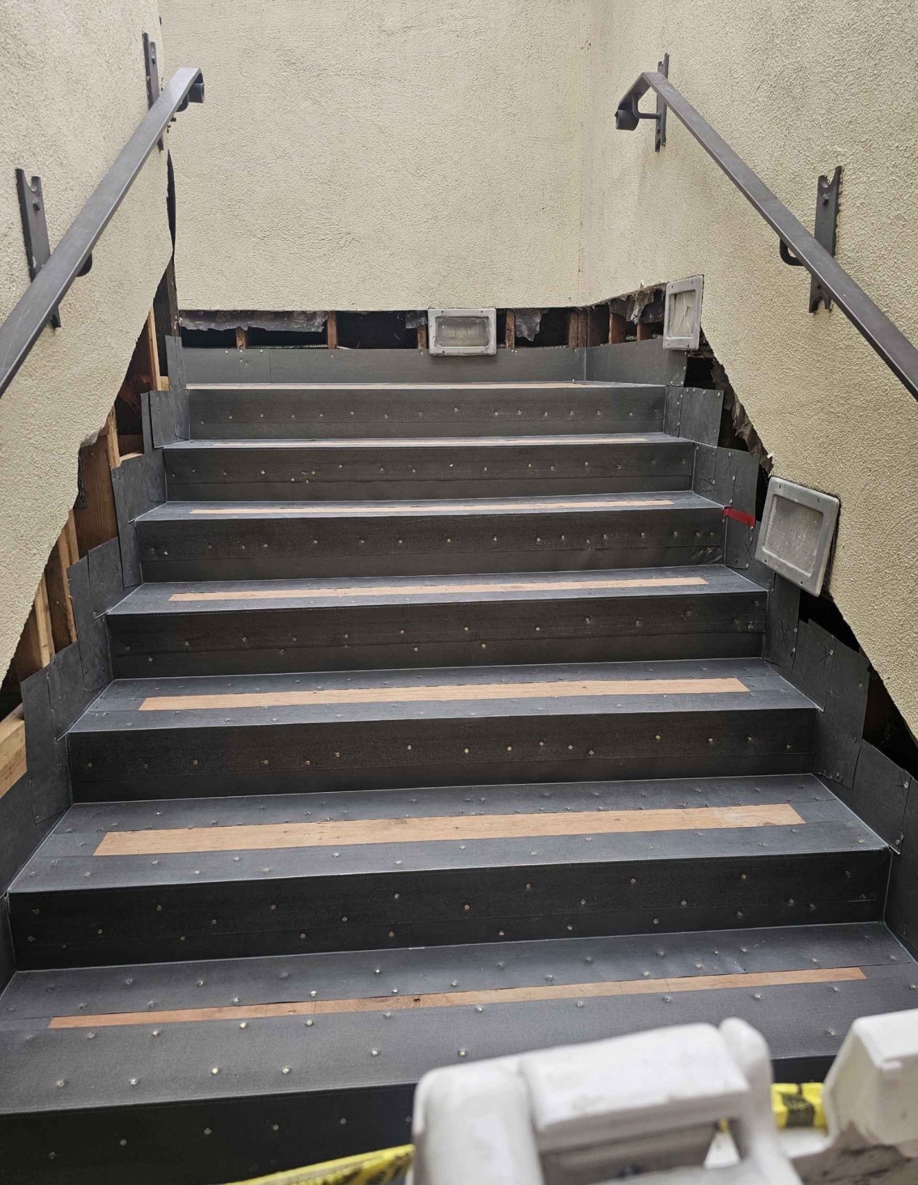 Front view of outdoor concrete staircase prepared with waterproofing membrane liners and metal handrail