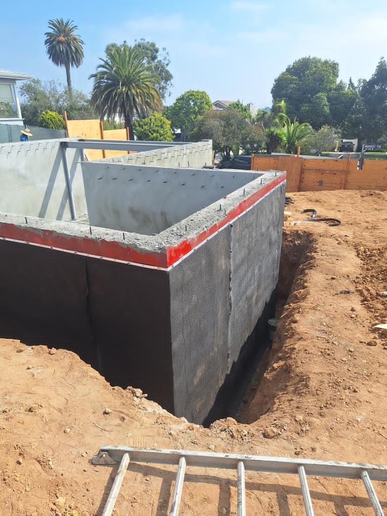 External concrete foundation retaining wall with red tape seals and damp-proofing membrane
