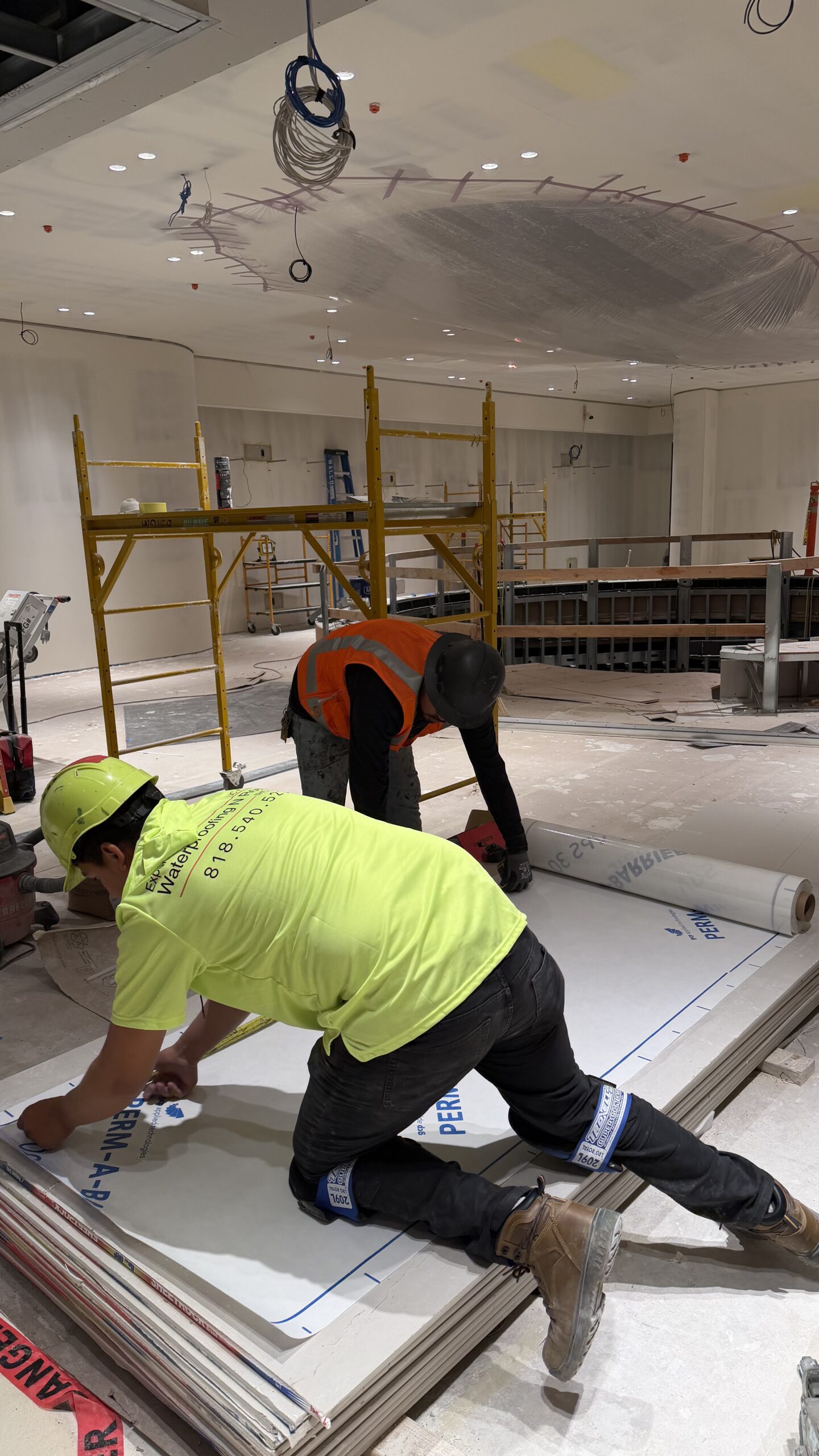 Contractor kneeling to cut and measure insulation board inside a residential interior space