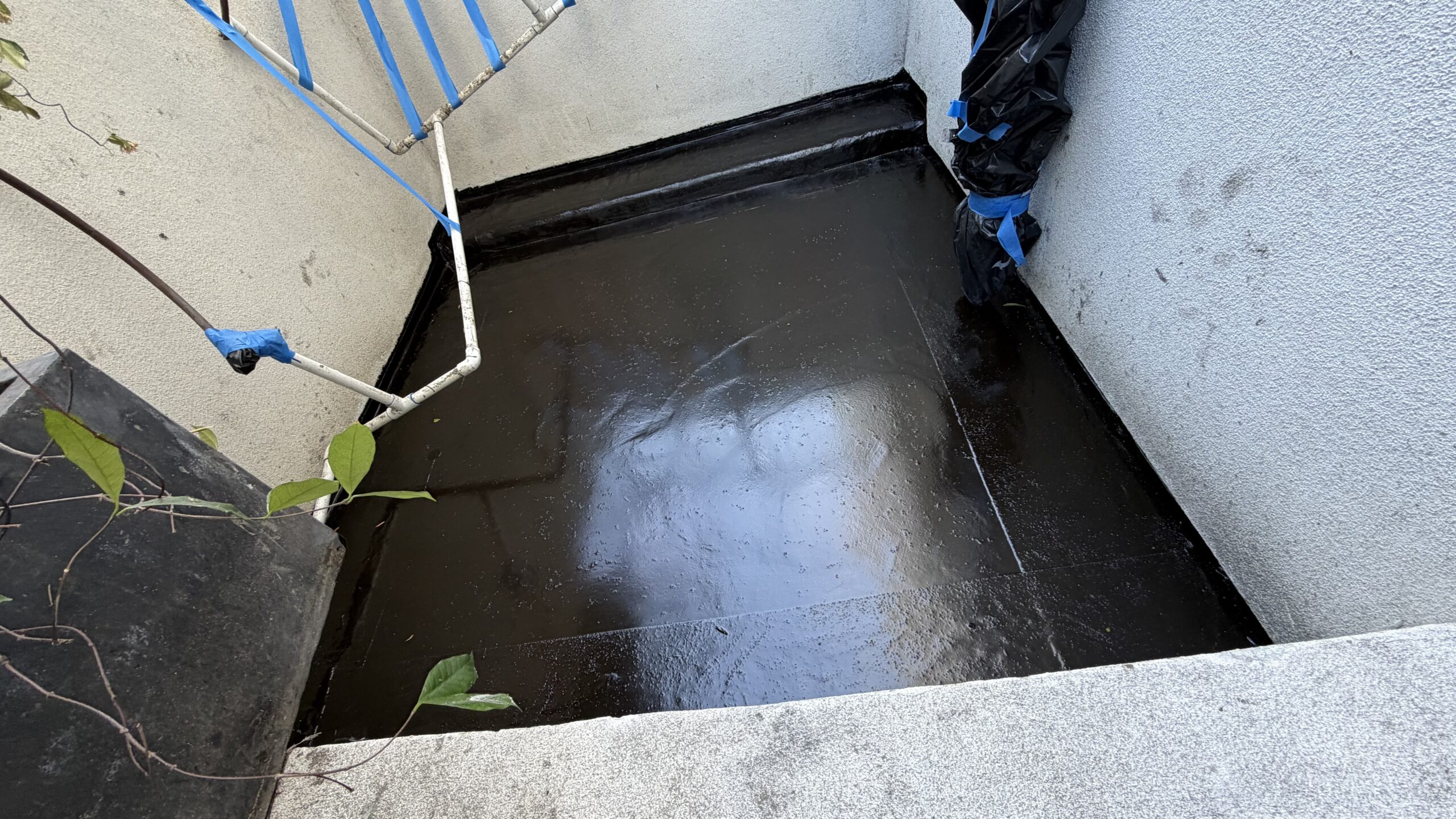 Dark elastomeric waterproofing coating applied inside a depressed concrete elevator or utility pit