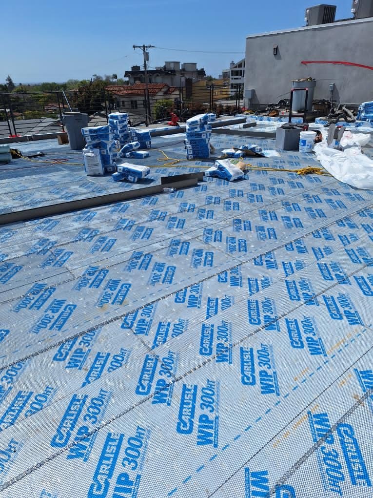 Rolls of Carlisle WIP 300 self-adhered sheet membrane laid out across a large roof deck surface