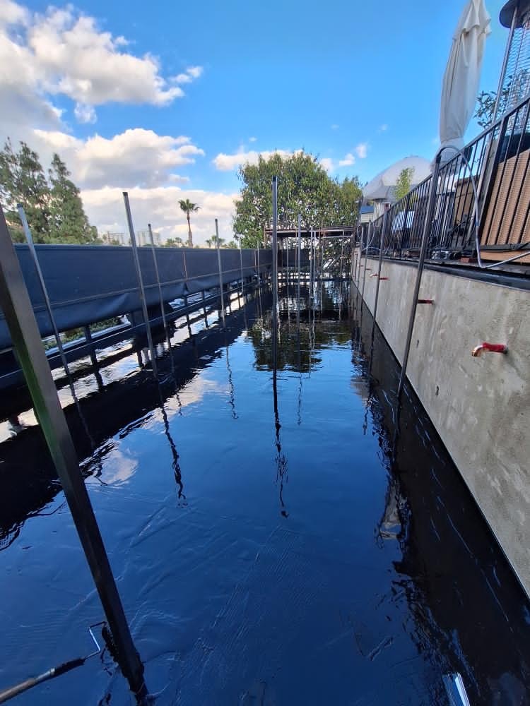 Narrow shored foundation trench with black waterproofing membrane along retaining walls