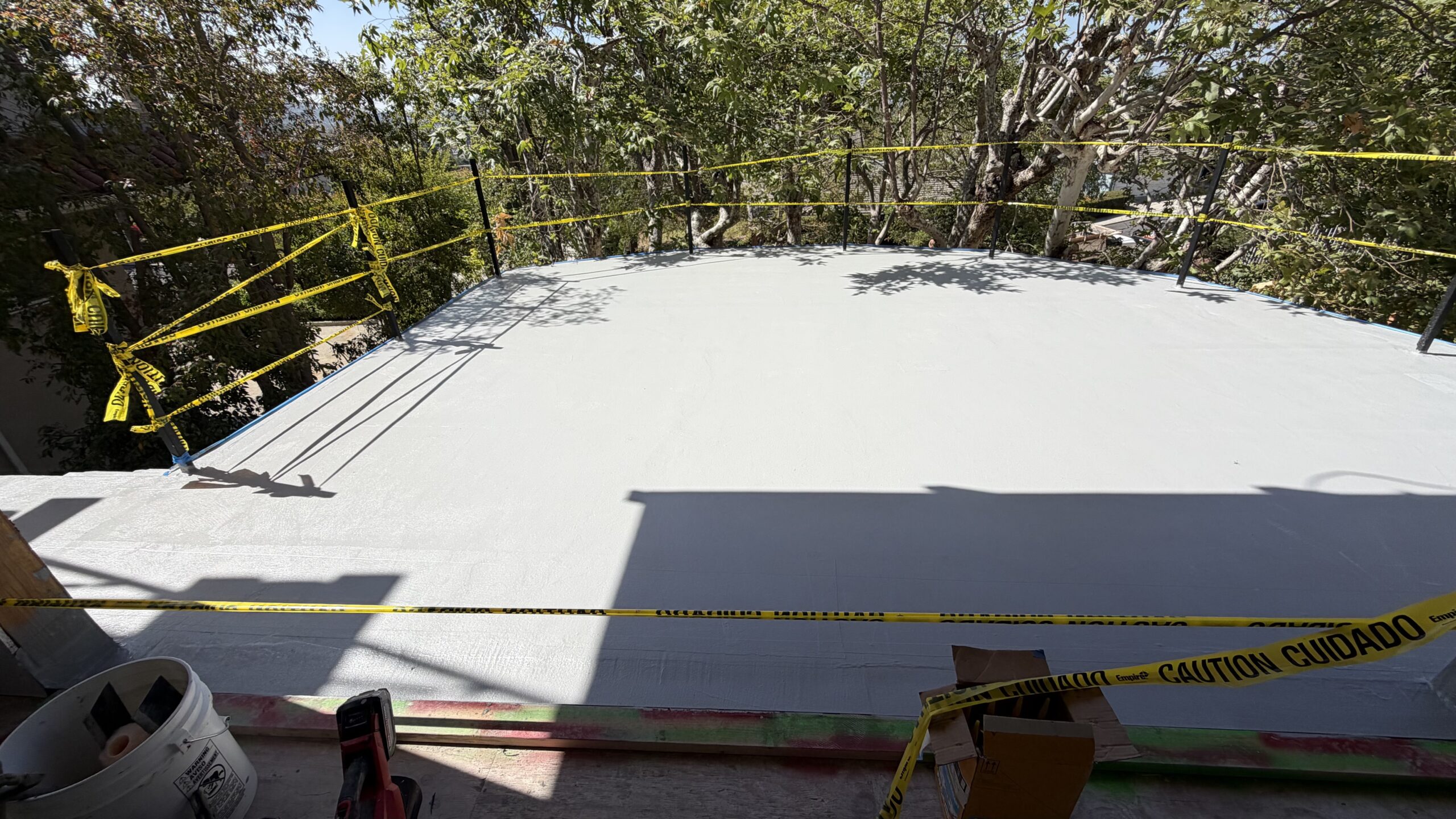 Caution tape surrounding freshly waterproofed open-air roof deck during curing process