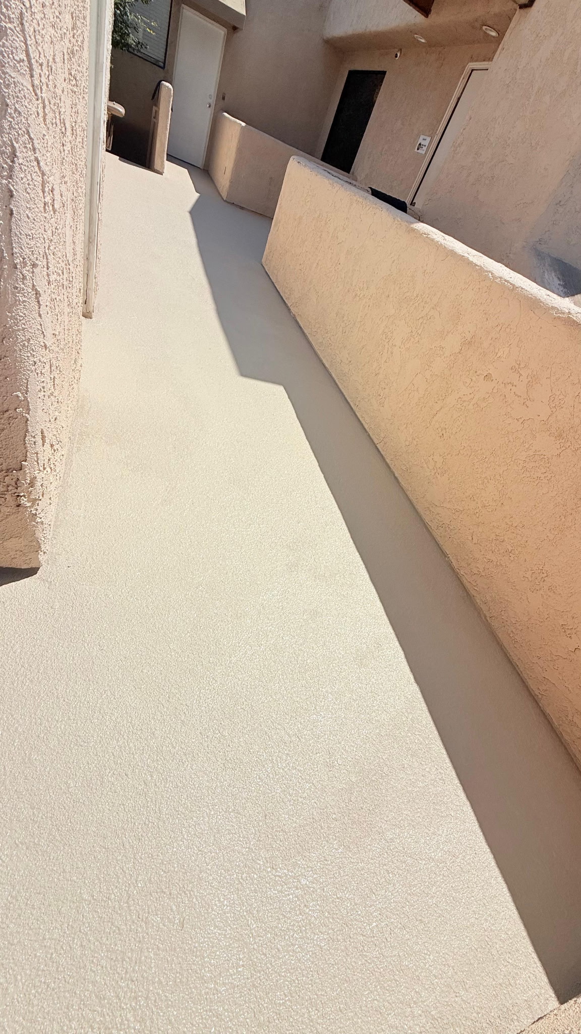 Smooth textured non-skid deck sealer applied along residential corridor balcony walkway