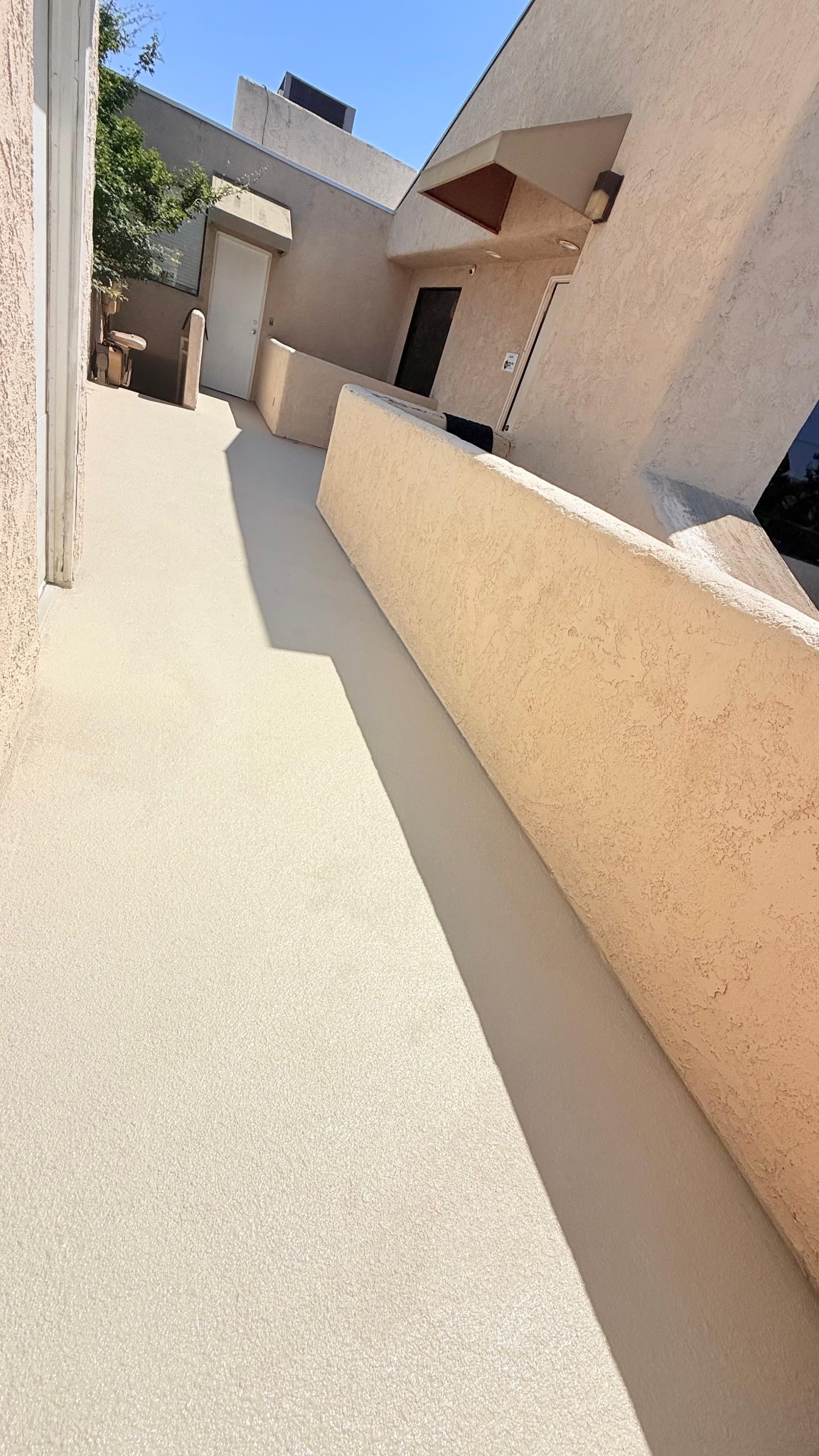 Bright sunlight highlighting tan textured waterproof sealer on residential corridor walkway